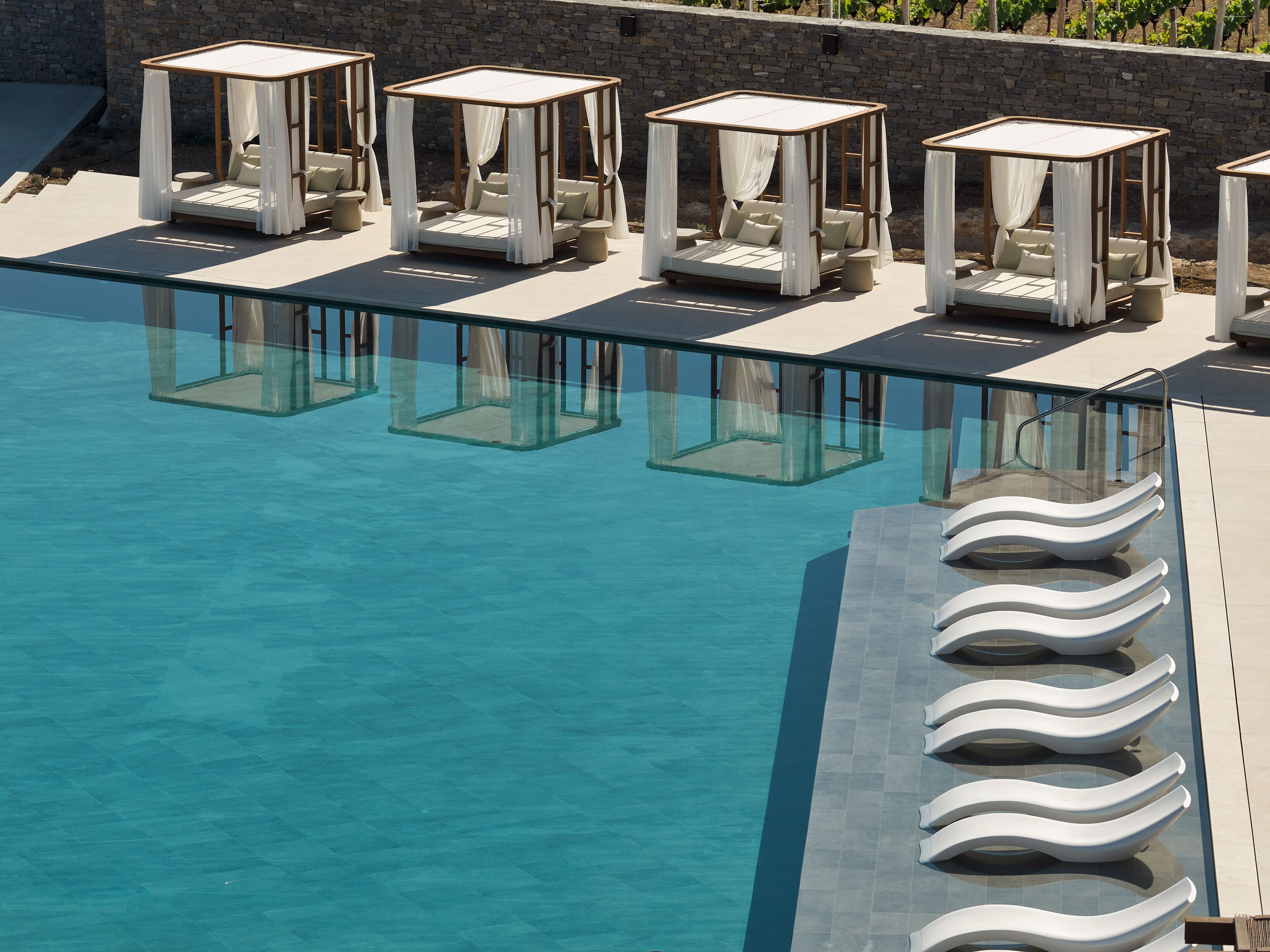 A poolside area with multiple sunbeds and a clear pool.
