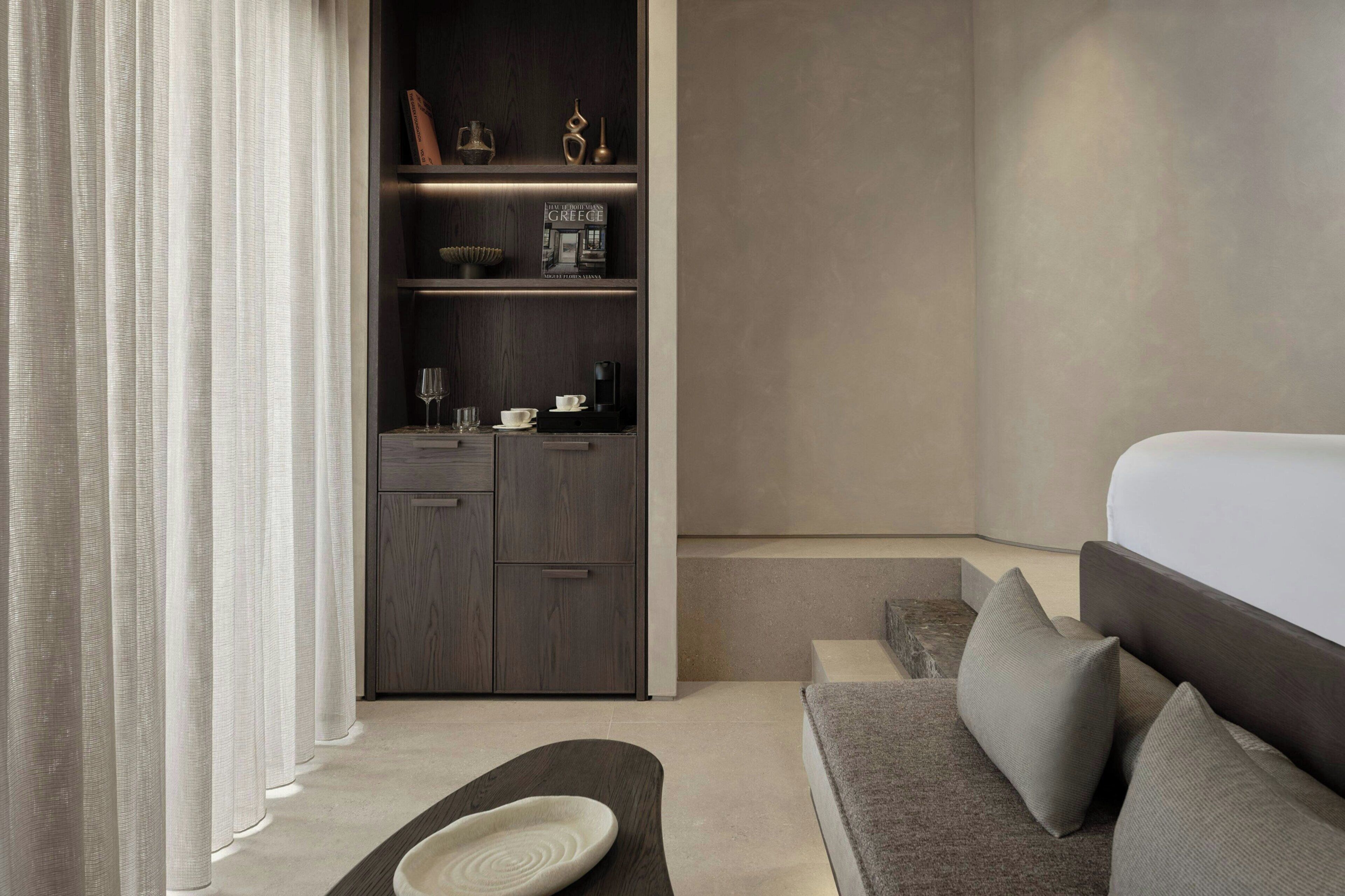 Una habitación de hotel moderna con una cama, un sofá, un armario empotrado y una mesita con un cuenco decorativo.