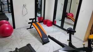 A gym with exercise equipment, including a treadmill and a bench, and red exercise balls.