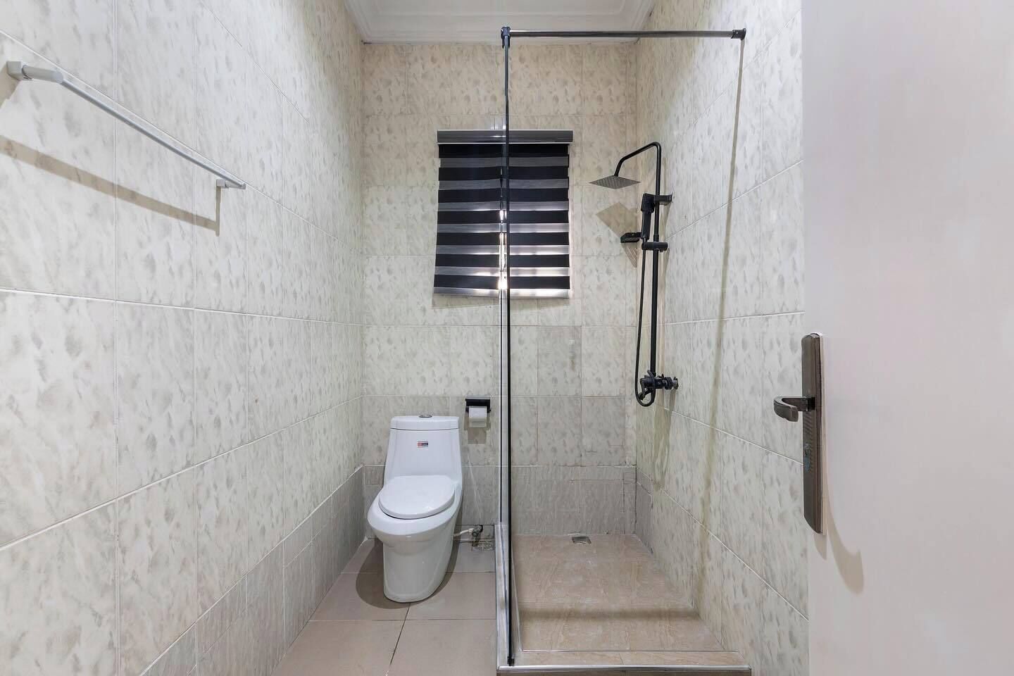 A small, modern bathroom with a glass-enclosed shower, a toilet, and a towel rack.