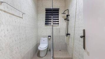 A small, modern bathroom with a glass-enclosed shower, a toilet, and a towel rack.