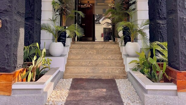 A hotel entrance with a central staircase, stone pillars, and potted plants.
