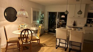 A dining area with a round table, chairs, and a Christmas tree. - Charming Beach Cottage with Hot Tub only 1 Mile to Gulf! (Naples)