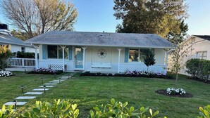 A house with a front porch, a star decoration, and a well-maintained lawn. - Charming Beach Cottage with Hot Tub only 1 Mile to Gulf! (Naples)