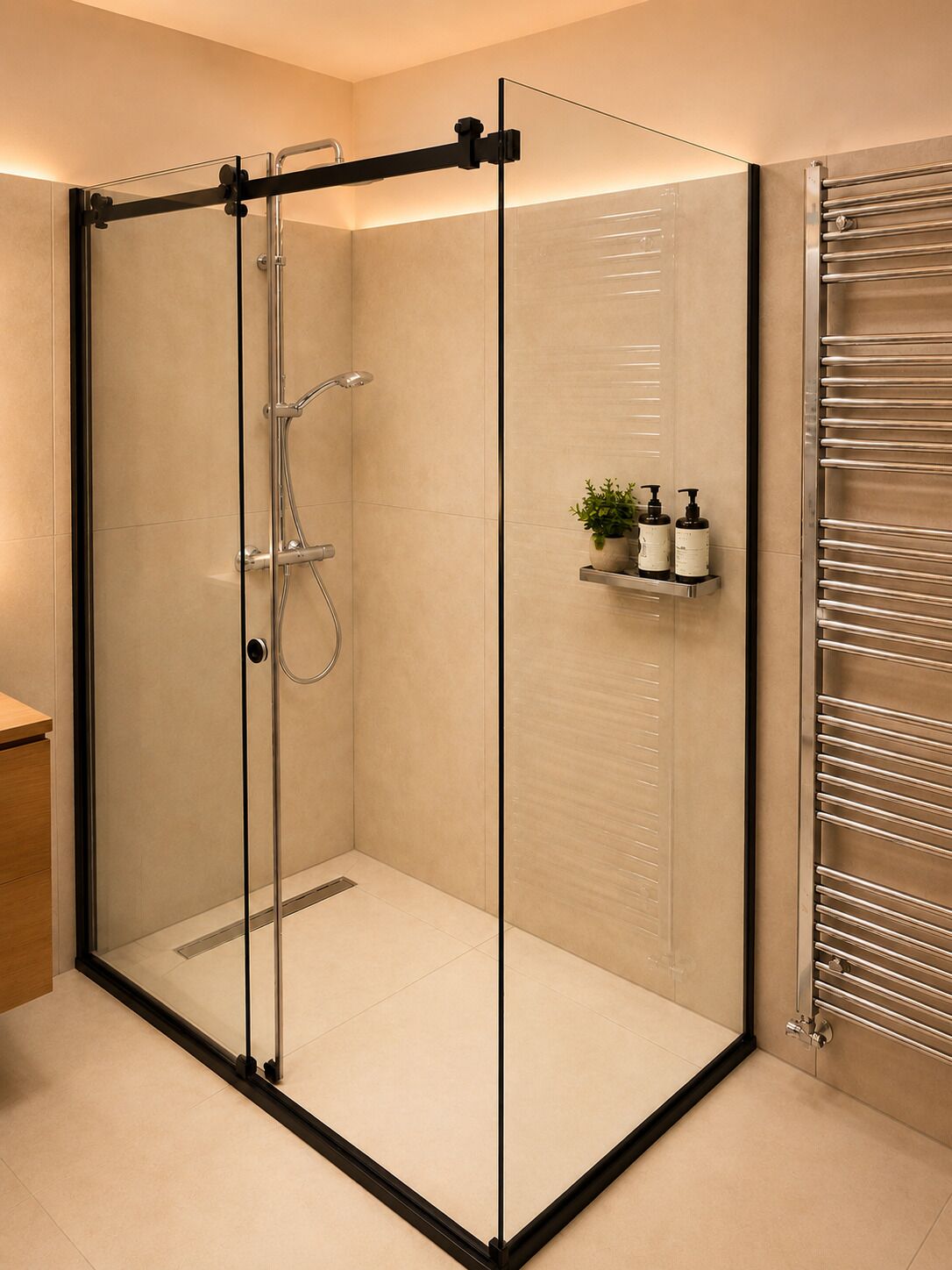 A glass-enclosed shower with a handheld showerhead, a glass door, and a towel rack with bottles.