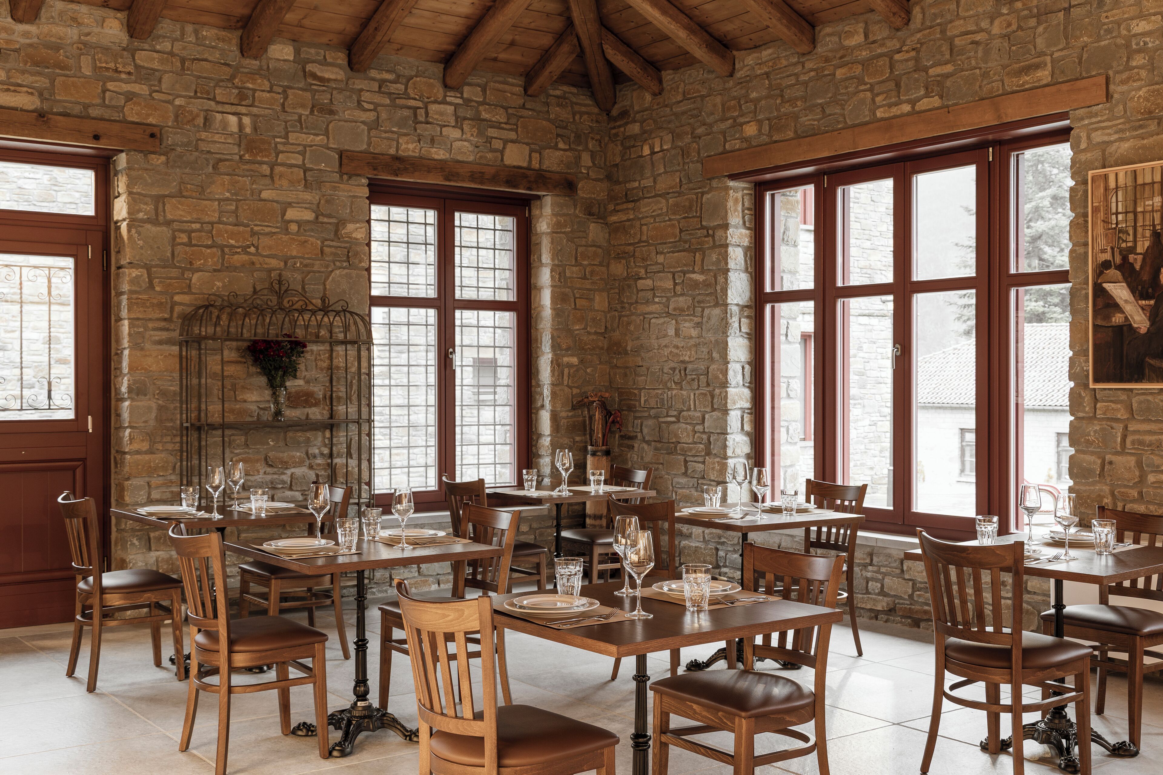 A dining area with stone walls, wooden tables, and chairs.
