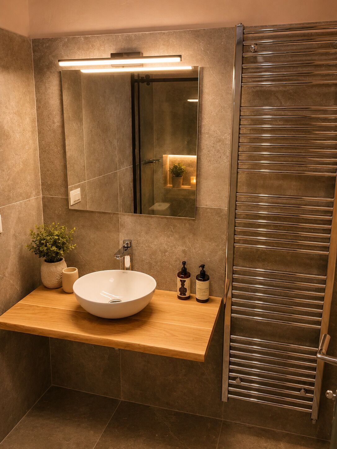 Un baño moderno con un espejo grande, un lavabo redondo y una ducha con puerta de vidrio.