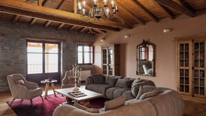 Ein geräumiges Wohnzimmer mit einer großen Eckcouch, Holzboden, Steinwänden und einem roten Teppich.