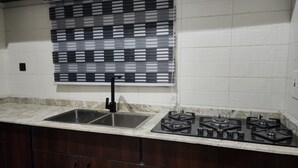 Cucina con lavello a due vasche, piano cottura a gas e persiana alla finestra con motivo bianco e nero.