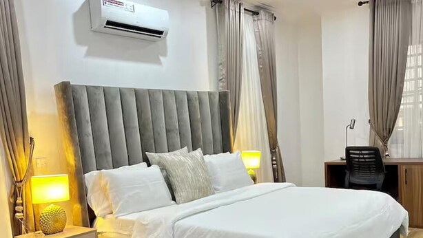 Camera da letto moderna con un letto grande, lampade da comodino, condizionatore d'aria e una scrivania con sedia.