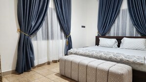 Una camera da letto con un letto, un comodino e una finestra con tende.