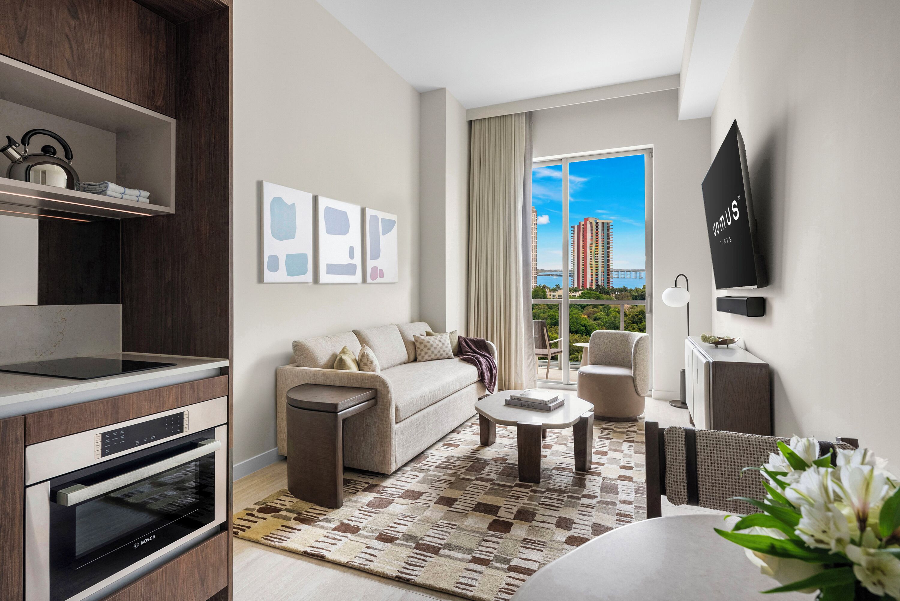 A modern living room with a sofa, coffee table, and a view of a cityscape.