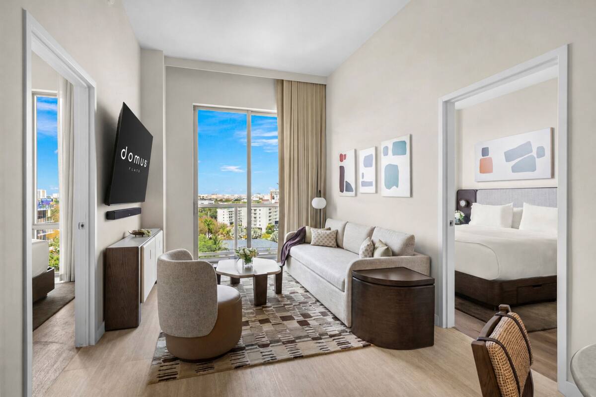 Una habitación de hotel moderna con sofá, sillón, mesita de centro y cama.