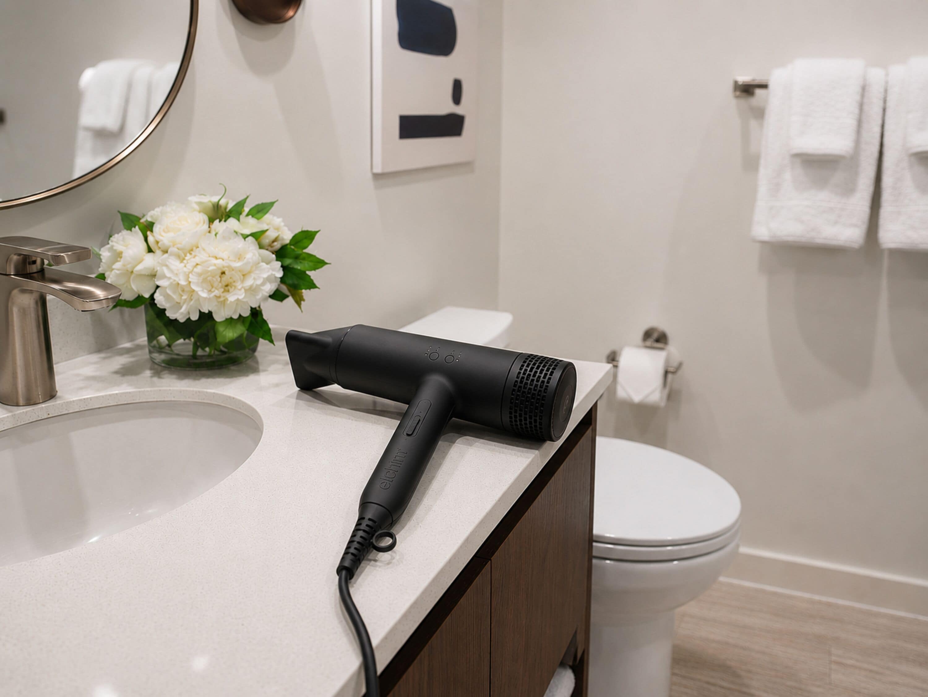 Een badkamer met een wastafel, haardroger, toilet en spiegel.