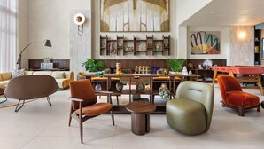 Un amplio espacio de sala con muebles modernos, una mesa de billar y un cuadro abstracto grande.