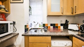 Une cuisine compacte équipée d’un four à micro-ondes, d’un grille-pain, d’un évier et d’un lave-linge.