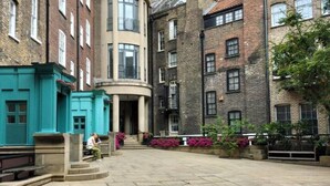 Une cour intérieure avec une fontaine centrale, entourée d’immeubles à plusieurs étages aux façades en briques et aux grandes fenêtres.