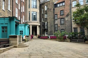 A courtyard with a central fountain, surrounded by multi-story buildings with brick facades and large windows. - Argyl | Covent Garden Studio Apt. (London)