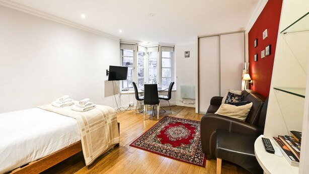 Une chambre d’hôtel avec un lit, un bureau, une chaise, une télévision et un mur d’accent de couleur rouge.