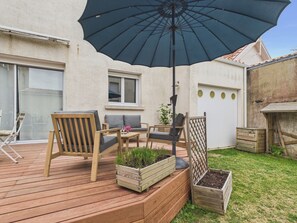 A wooden deck with outdoor furniture, a large umbrella, and raised garden beds. - House for 8 with garden, Saint-Gilles town centre (Saint-Gilles-Croix-de-Vie)