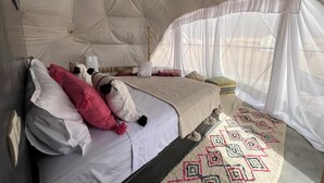 Un dormitori amb tenda, un llit, almoinos i una catifes amb dibuixos.