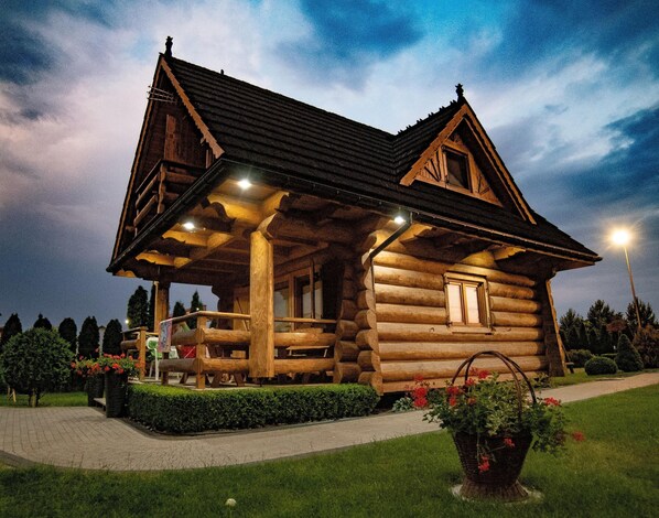 Une cabane en rondins avec un porche, une fenêtre et un chemin qui y mène.