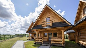 A wooden lodge with a paved driveway, a covered porch, and a fenced property. - Comfortable, Large Holiday Homes With Terraces (Darlowo)