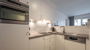 A modern kitchen with white cabinetry, a built-in oven, a dishwasher, and a stainless steel sink. - Knokke City Centre Apartment for 6 (Knokke-Heist)