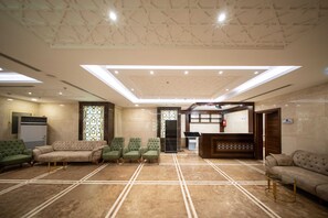 A hotel lobby with a reception desk, seating area, and a patterned ceiling. - Tamore Hotel By Orvana (Makkah)