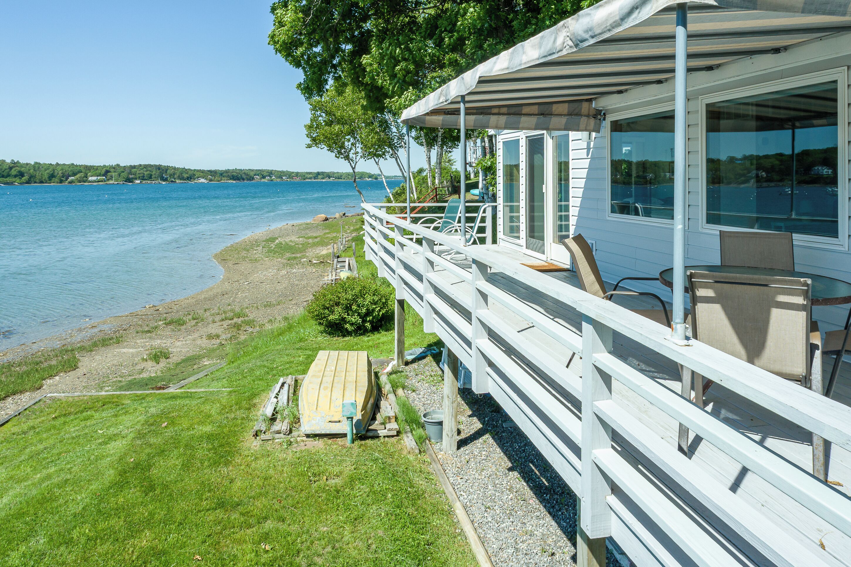 A waterfront property with a deck, outdoor seating, and a view of the lake.