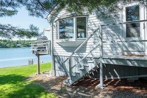 A lakeside cabin with a deck, a staircase, and a window overlooking the water. - Eider Haven: 1  BR, 1  BA Cottage in Harpswell, Sleeps 4 (Harpswell)