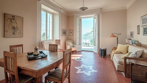 Un coin repas avec une table et des chaises en bois, un canapé et, par une porte ouverte, une vue sur un patio extérieur.