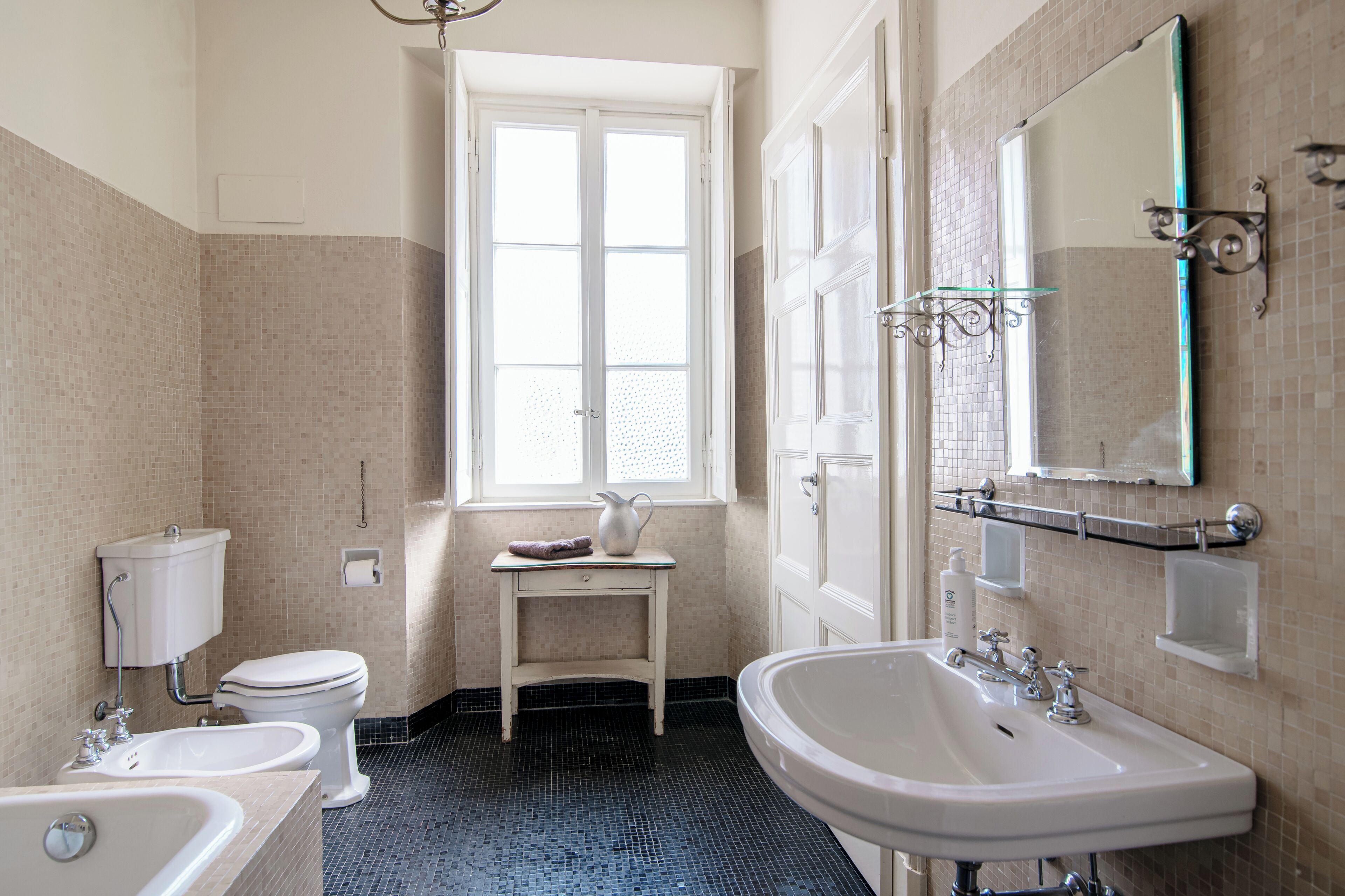 A bathroom with a toilet, bidet, sink, and a mirror.