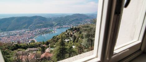 A view from a window overlooking a town with a lake, surrounded by hills.