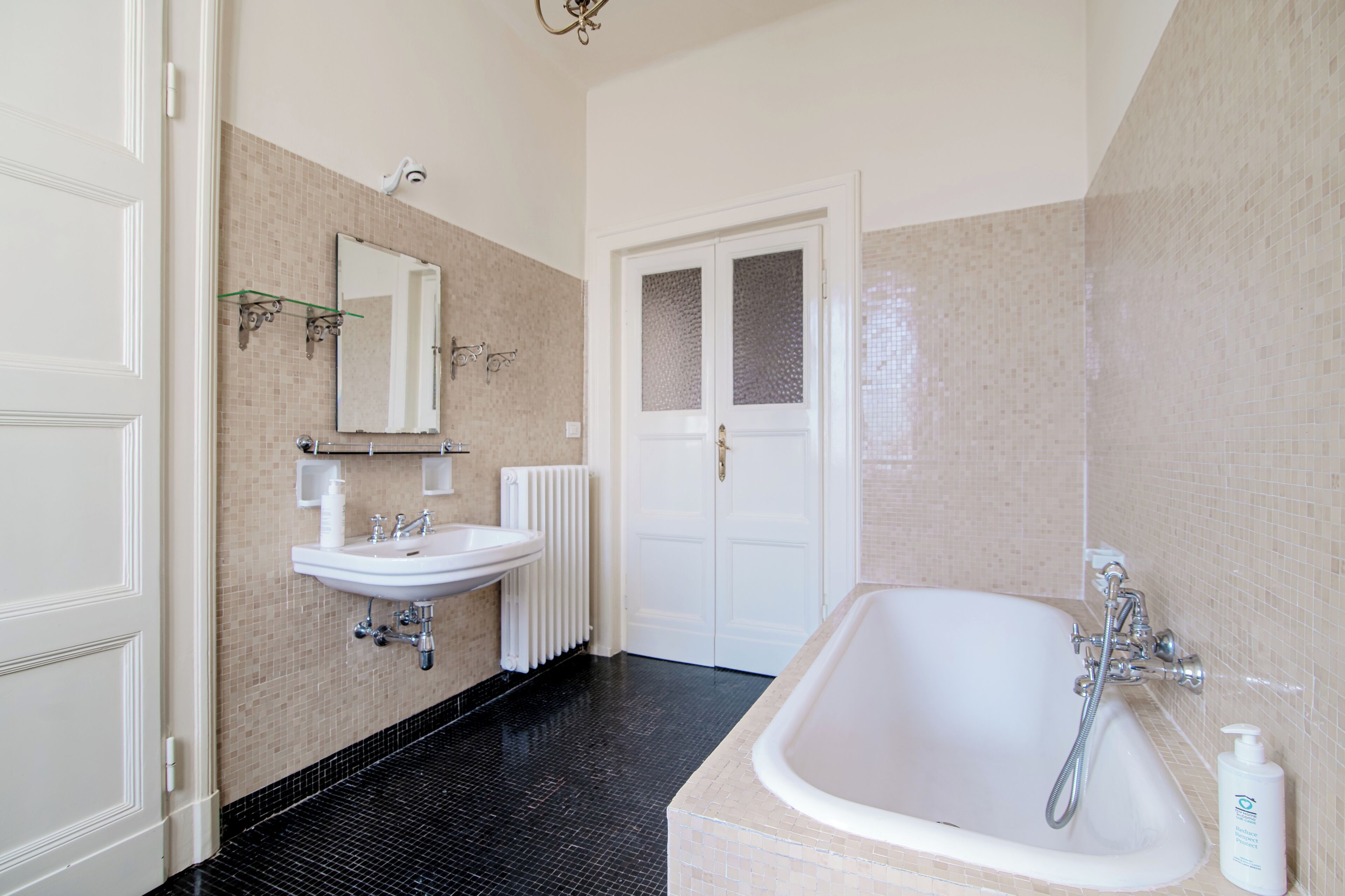 Une salle de bain avec un lavabo blanc, un miroir et une baignoire.