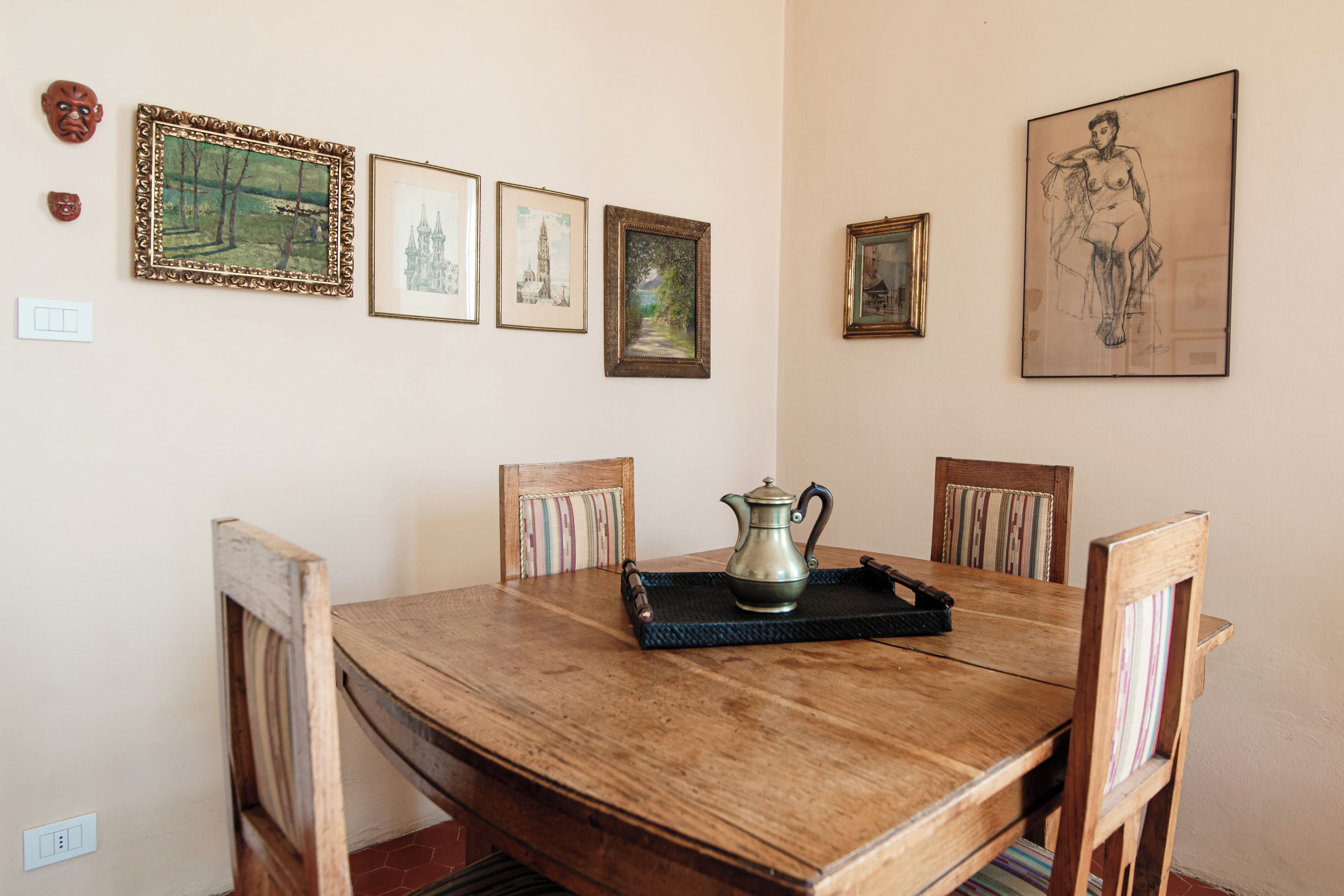 Een eethoek met een houten tafel, stoelen en een dienblad met een theepot.