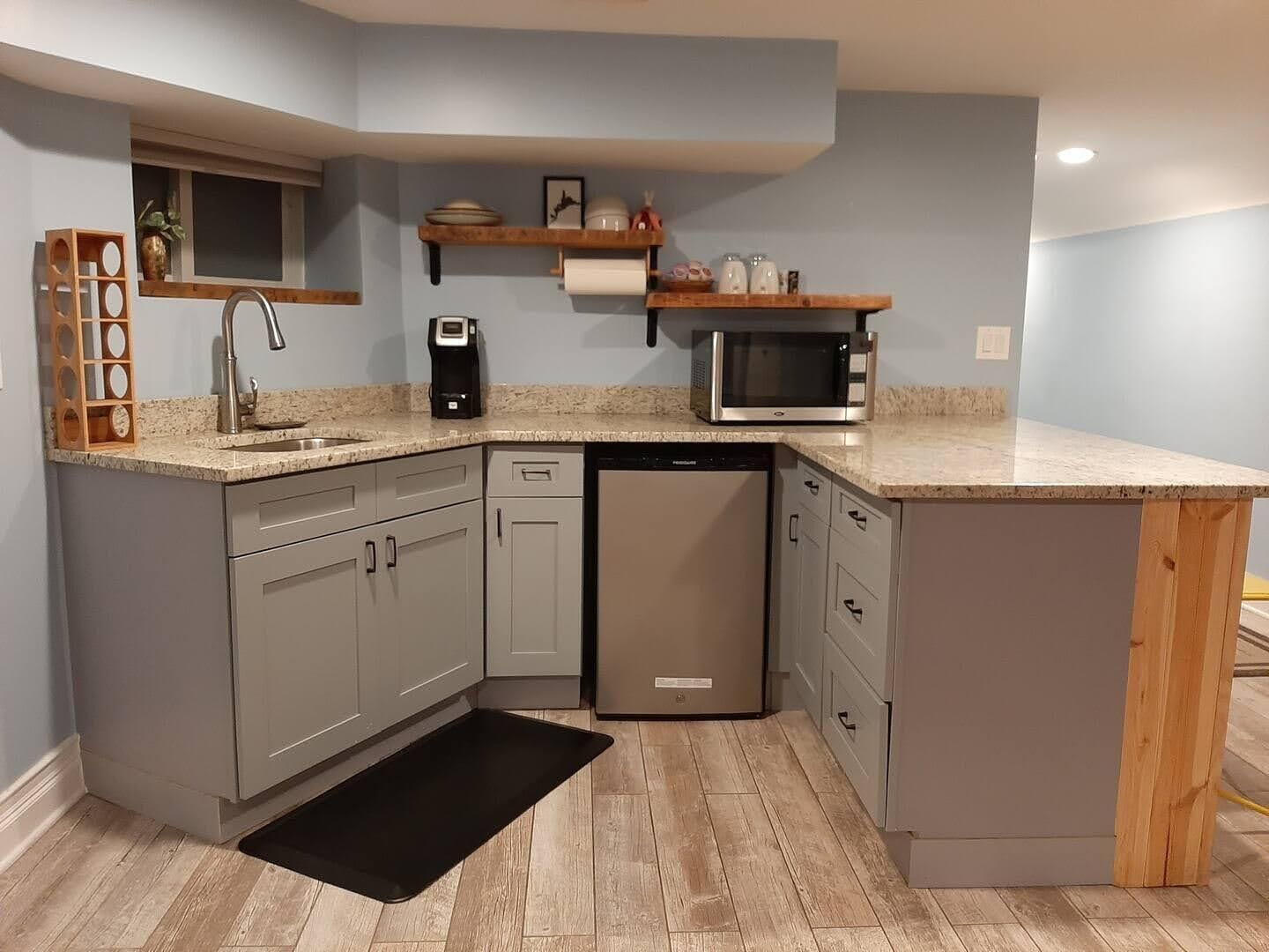 A compact kitchen with grey cabinets, a dishwasher, a microwave, and a coffee maker.
