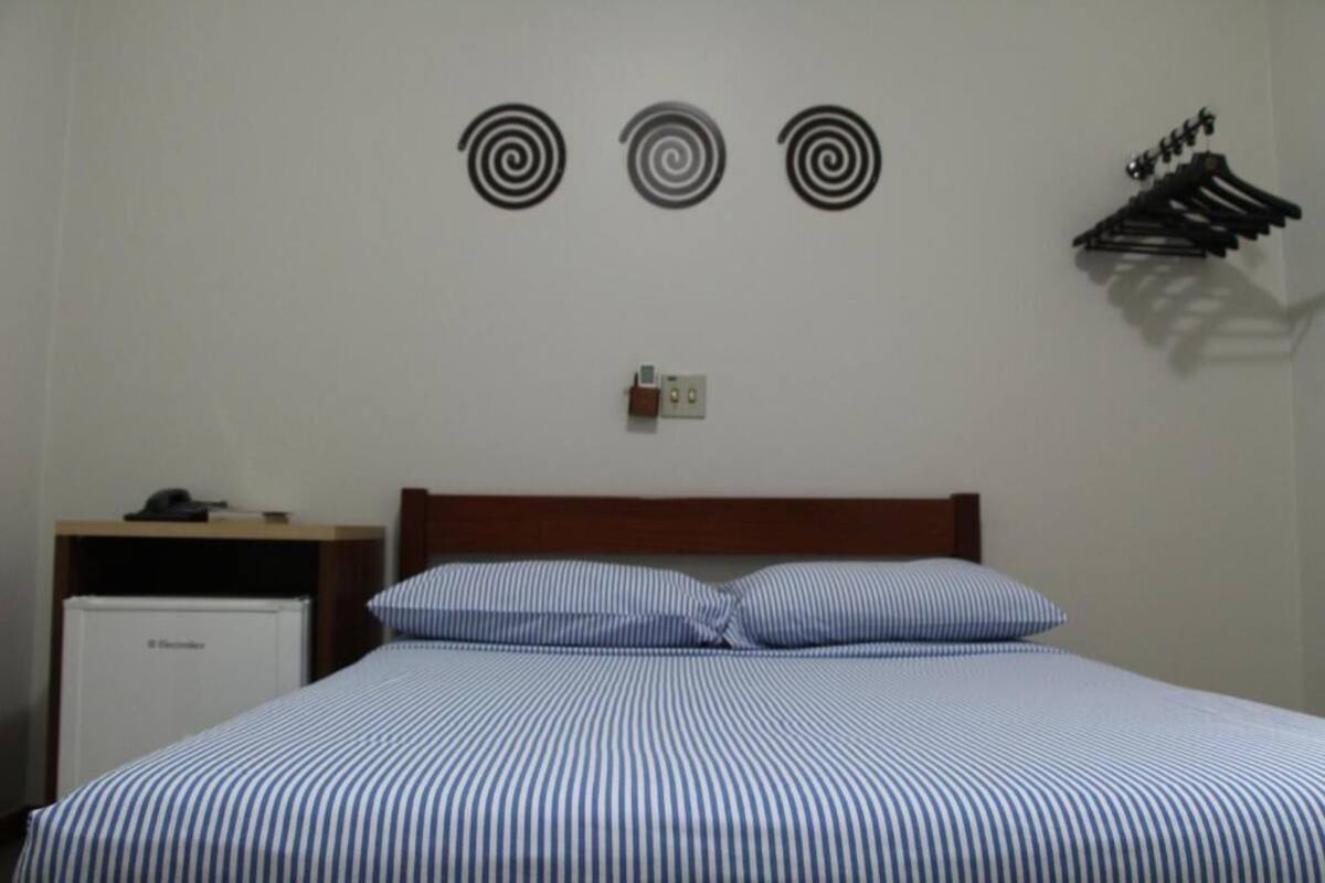 Ein Hotelzimmer mit einem Bett, einem kleinen Schreibtisch, einem Kühlschrank und Wanddekorationen.