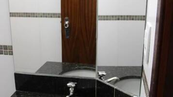 A bathroom with a black granite countertop, a white sink, and a wooden door.