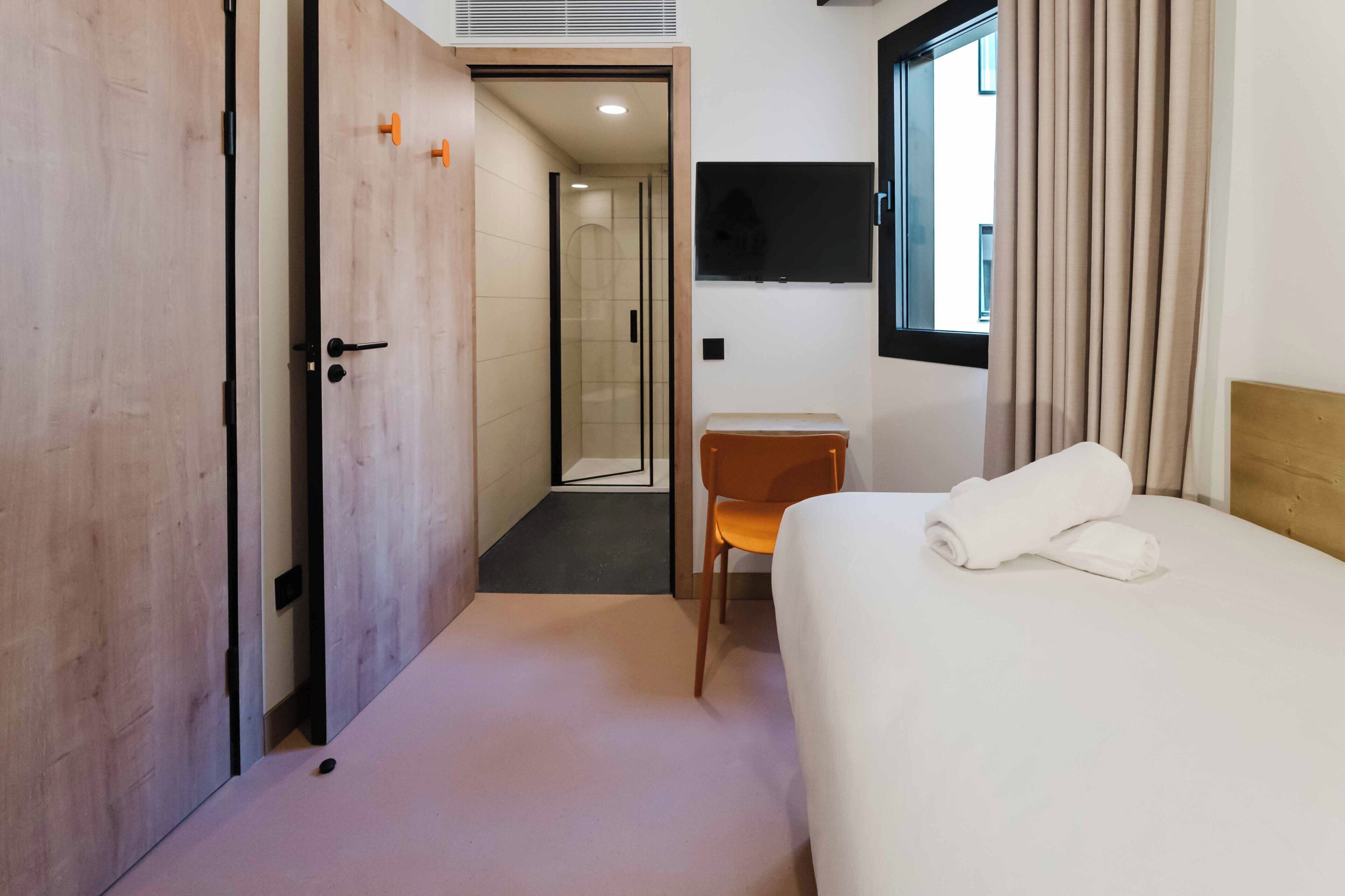 Une chambre d’hôtel équipée d’un lit, d’un bureau, d’une chaise, d’une télévision et d’une salle de bain avec douche.
