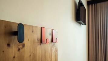 Un mur en bois avec un objet noir et deux crochets rouges.
