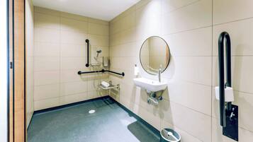 Une salle de bain moderne équipée d’une barre d’appui, d’un lavabo, d’un miroir et d’une poubelle.
