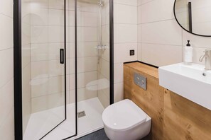 Ein modernes Badezimmer mit einer Duschkabine aus Glas, einer weißen Toilette und einem Holzwaschtisch mit Waschbecken.