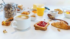 En frukostuppsättning med en kaffekopp, croissanter och ett glas apelsinjuice.