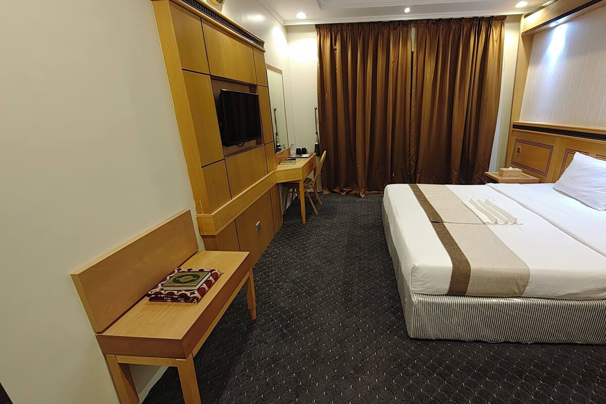 A hotel room with a bed, a desk, a chair, a television, and a window with curtains.