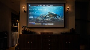Sistema de cine en casa con una pantalla grande mostrando una película titulada 'OUR PLANET IF'.