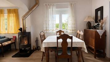 Un coin repas chaleureux avec une table dressée pour quatre personnes, un poêle à bois et une vue par la fenêtre.