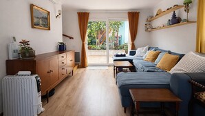 Una sala de estar con un sofá, un mueble de madera, una mesita y vistas al exterior a través de un ventanal.