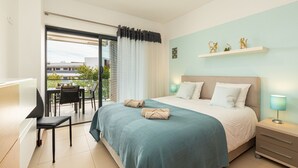 Habitació d'hotel moderna amb un llit gran, una taula de treball i un balcó amb vistes.