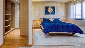 Een moderne slaapkamer met een bed, nachtkastjes, een kledingkast en een raam met gordijnen.
